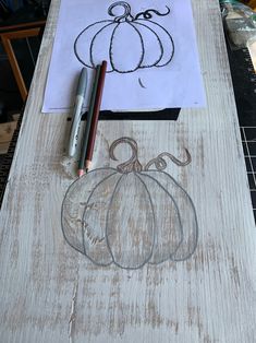 a drawing of a pumpkin on a piece of wood next to a pen and paper