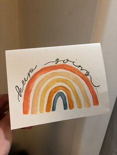 someone holding up a card with a rainbow painted on it