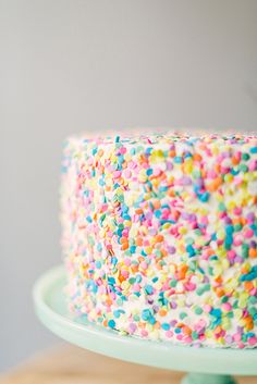 a sprinkle covered cake sitting on top of a wooden table