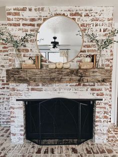 the fireplace is decorated with pumpkins and greenery in front of a round mirror