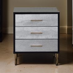 a white and black nightstand with two drawers on it's sides next to a bed