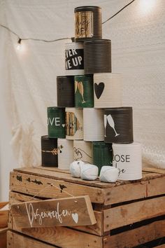 a stack of coffee cups sitting on top of a wooden crate next to a string of lights