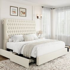 a white bed sitting in a bedroom on top of a rug next to a window