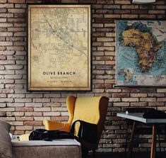 a living room filled with furniture and a map hanging on the brick wall above it