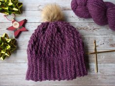 This gorgeous hat is brimming with texture! It is a deep, saturated royal purple color and has a faux fur pom accent.  It is lined with a soft, creamy, white ,fleece to add an extra layer of warmth and to avoid the itchiness that some people experience when wearing wool. It is meant to fit a large head, measuring about 22-23" around. It is loose fitting and slouchy and extremely comfortable! If you're looking for the kind of hat that stays in style season after season, you just can't beat a classic pom hat!        This item is created in Indiana using wool from our flock! It was shorn here by my husband then shipped to Harmony, Maine to be processed by Bartlett Yarns . Their spinning process creates a fisherman yarn that has amazingly rich color and texture!   It was then returned to our f Comfortable One-size Beanie In Specific Color, Warm Purple Crochet Hat, Purple Yarn Beanie Hat, Sock Hat, Purple Winter Beanie One Size, Warm Purple Beanie Cap, Royal Purple Color, Sox Hat, Kinds Of Hats