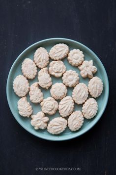 a blue plate filled with small cookies on top of a black countertop next to a knife and fork