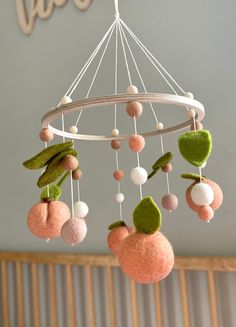 a mobile made out of felt balls and leaves hanging from the ceiling in a child's room