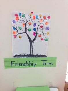 a toilet seat with a tree painted on the wall above it and a sign that says, friendship tree