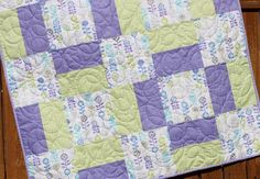 a purple and green quilt on top of a wooden fence