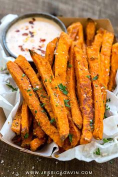 baked sweet potato wedges in a basket with dipping sauce on the side and garnished with parsley