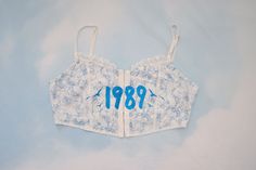 On the front, 1989 with seagulls and on the back "in your wildest dreams," lyrics in sparkle blue vinyl on the front on a blue and white flower crop top. upcycled from cider size small 34" bust Wildest Dreams Lyrics, Flower Crop Top, Wildest Dreams, Blue Vinyl, Fort Lauderdale, White Flower, Cropped Top, Cider, Halloween Shopping