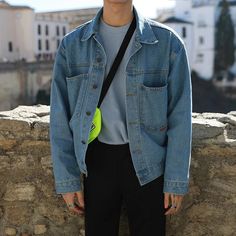 a young man standing next to a stone wall