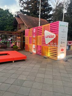 an orange couch sitting on top of a sidewalk next to a pink box and some trees