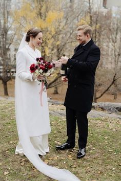 a bride and groom are standing in the grass with their hands together, smiling at each other