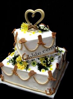 two tiered wedding cake decorated with flowers and hearts on the top, sitting on a black surface