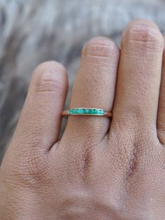 a person's hand with a ring on it that has an emerald stone in the middle