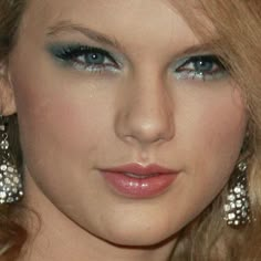 a close up of a woman with blue eyes and blonde hair wearing large diamond earrings