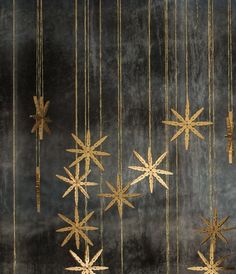 several gold stars hanging from strings on a wall in front of a black background with white dots