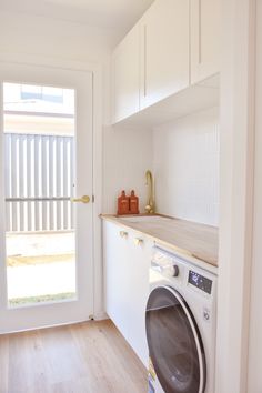 a washer and dryer in a room with white walls, wooden floors and doors