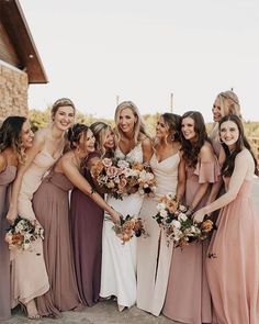 a group of women standing next to each other wearing dresses and holding bouquets in their hands