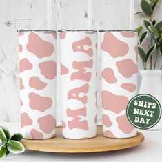 three pink and white cow print tumblers on a wooden tray