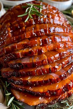 sliced ham on a platter with rosemary sprigs