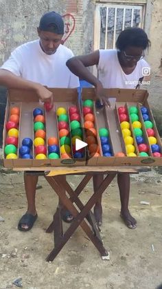 two men are playing with colorful balls in a box