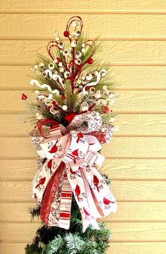 a decorated christmas tree with red, white and green bows on it's top