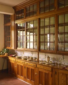 an old fashioned kitchen with wooden cabinets and glass doors on the wall, along with pots and pans