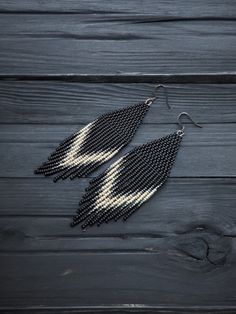 black and white beaded earrings on wooden planked surface with beads hanging from them