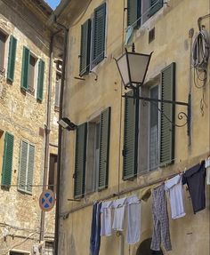 clothes hanging out to dry in front of an old building with green shutters and windows