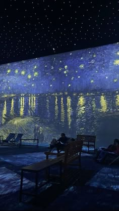 people are sitting on benches in front of a starry night sky over the water