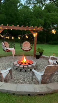 an outdoor fire pit surrounded by chairs and lights