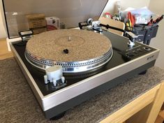 a turntable sitting on top of a table with other items in the back ground