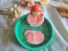 there is a cake in the shape of a doll sitting on a green plate next to flowers