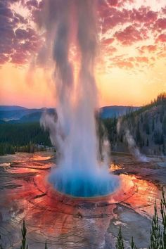 a geyser spewing water into the sky at sunset