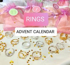 a table topped with lots of rings next to pink bags filled with gold and white stars