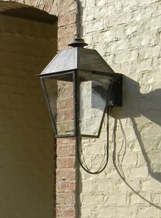 an old fashioned street light on the side of a brick building in front of a door