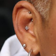 a man with three piercings on his ear looking at the other side of his ear