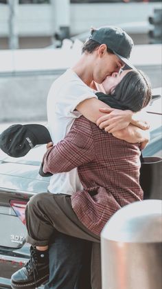 a man and woman hugging on the back of a car