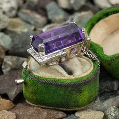 This stunning 14K white gold pendant is centered with one (1) cut-cornered rectangular step cut natural amethyst set into a four-prong setting. The amethyst is bordered with eighteen (18), bead set, round brilliant cut diamonds. The pendant measures 27.0mm X 16.9mm X 13.3mm and is suspended from a 14K white gold cable link style neck chain measuring 18 inches in length. Luxury Purple Amethyst Ring, Rectangular Shape, Luxury Purple Amethyst Rectangular Ring, Luxury Purple Rectangular Amethyst Ring, Luxury Rectangular Amethyst Ring, Rectangular Platinum Jewelry With 17 Jewels, 14k White Gold Purple Gemstone Jewelry, Purple Gemstone Jewelry In 14k White Gold, Formal Purple Amethyst Ring With Rectangular Shape, Formal Rectangular Amethyst Ring