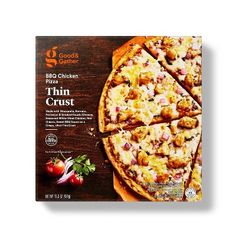 a box of thin crust pizza sitting on top of a wooden table next to tomatoes