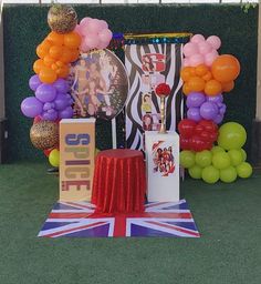 there are balloons and decorations on the grass near a wall with pictures in it, including an union jack flag