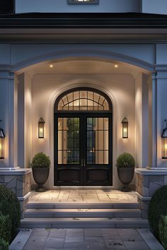 the front entrance to a house with two large planters on each side and lights on either side