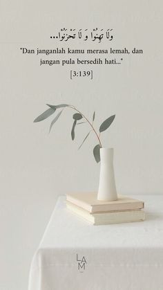 a white vase sitting on top of a table next to a stack of books and a plant