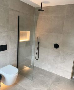 a bathroom with a toilet, shower and glass partition in the wall to separate it from the rest of the room