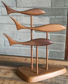 a wooden sculpture sitting on top of a table next to a brick wall and floor