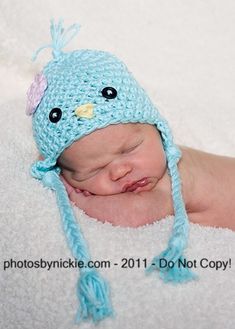 a newborn baby wearing a blue crocheted bird hat