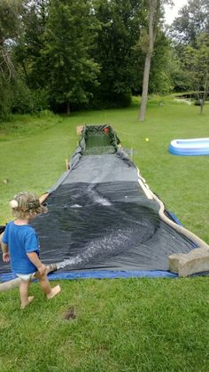 a young boy is playing in the yard with a large tarp over his face