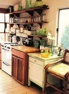 a kitchen with wooden cabinets and shelves filled with dishes on top of each shelf next to a window